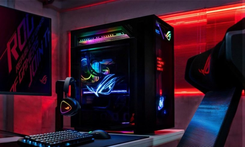 ROG G1000 gaming desktop at the centre of a red-lit gaming setup with a ROG monitor, RGB keyboard, mouse, headset on a stand and a ROG gaming chair